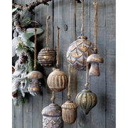 Fából készült, különböző formájú és méretű karácsonyfadíszek, szürke deszkafal előtt.