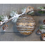 Antikolt, arany felületű, fából készült , gömb formájú karácsonyfadísz , havas fenyőággal.