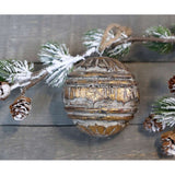 Antikolt, arany felületű, fából készült , gömb formájú karácsonyfadísz , havas fenyőággal.