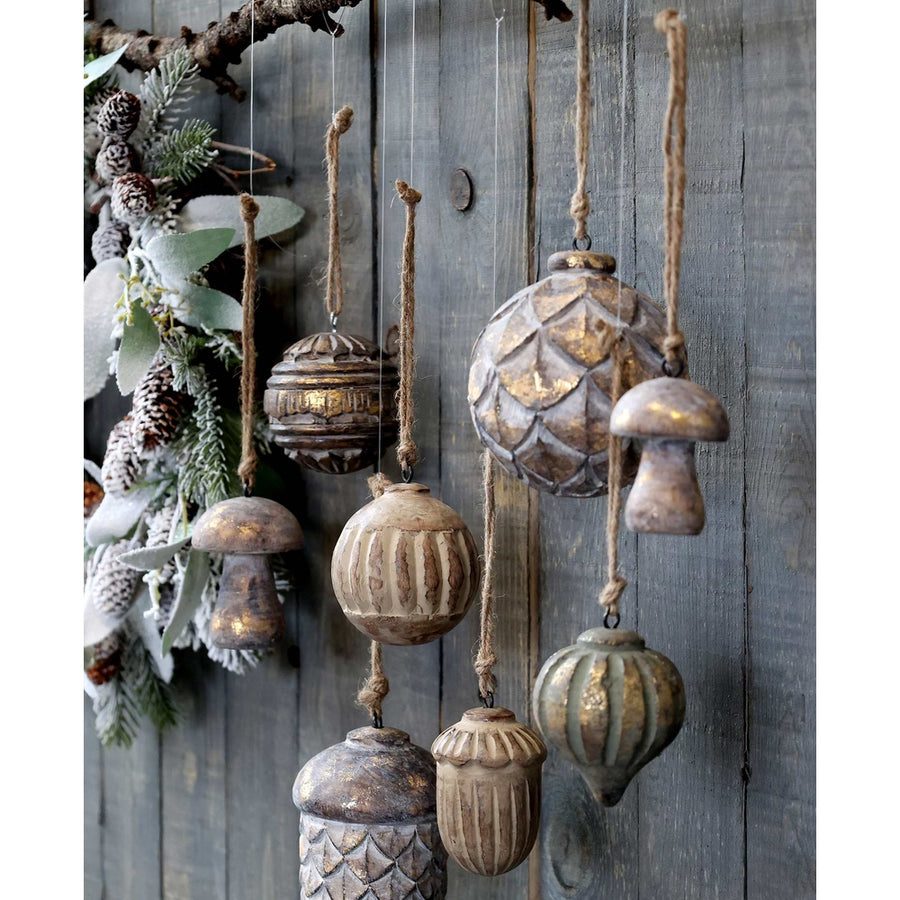 Fából készült, különböző formájú és méretű karácsonyfadíszek, szürke deszkafal előtt.