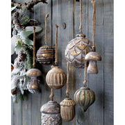 Fából készült, különböző formájú és méretű karácsonyfadíszek, szürke deszkafal előtt.