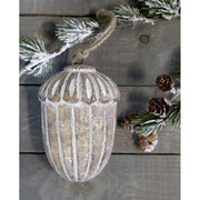 Vintage stílusú, mangófából faragott, 15 cm magas, antikolt felületű, tölgy makk formájú, kézműves karácsonyfadísz szürke deszkaasztalon havas fenyővel 