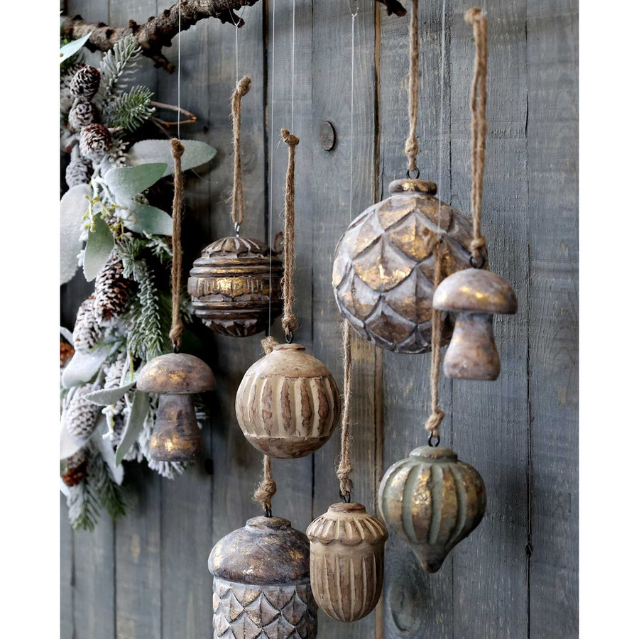 Fából készült, különböző formájú és méretű karácsonyfadíszek, szürke deszkafal előtt.