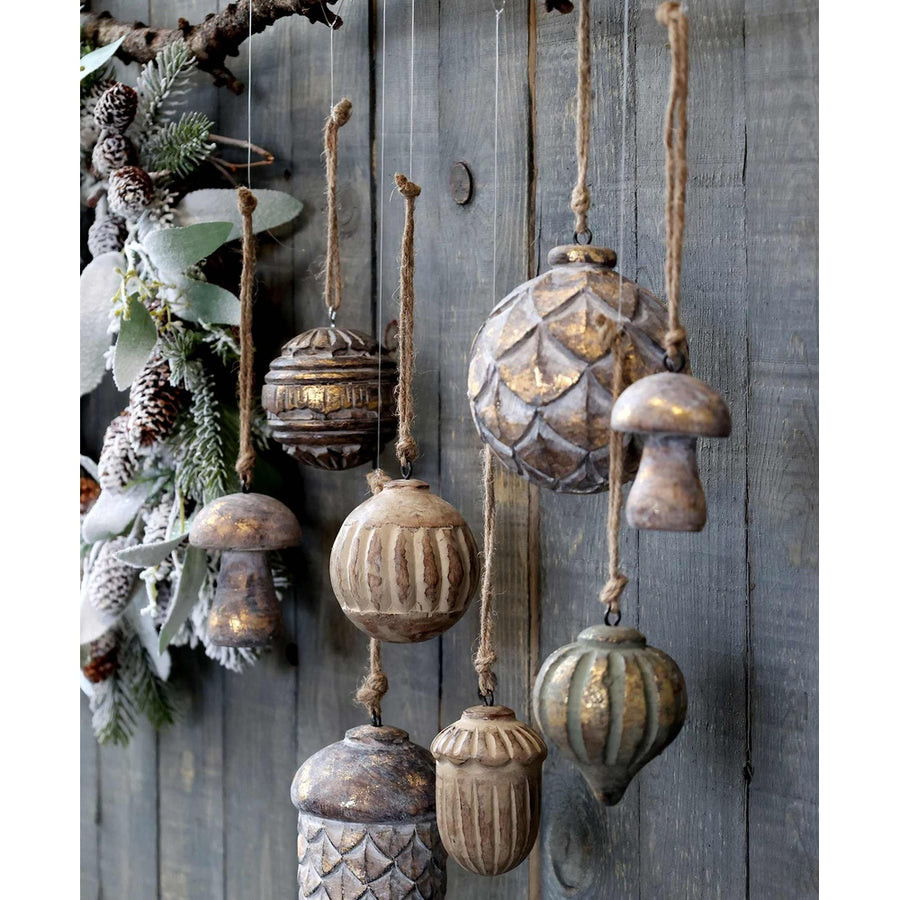 Fából készült, különböző formájú és méretű karácsonyfadíszek, szürke deszkafal előtt.