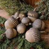 Vintage, rusztikus stílusú, 14 cm magas, fa hatású, antik arany színnel patinázott karácsonyi makk díszek fenyők között