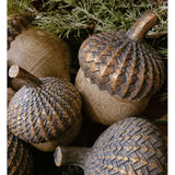 Vintage, rusztikus stílusú, 14 cm magas, fa hatású, antik arany színnel patinázott karácsonyi makk díszek fenyők között