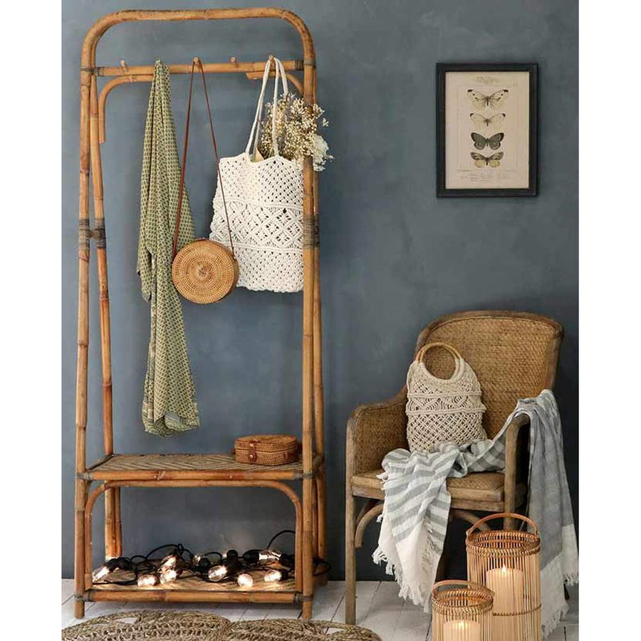 Vintage stílusú, autentikus, kör formájú, növényi rattanból és bőrből készült kézműves női táska bambusz fogason kék színű fal előtt