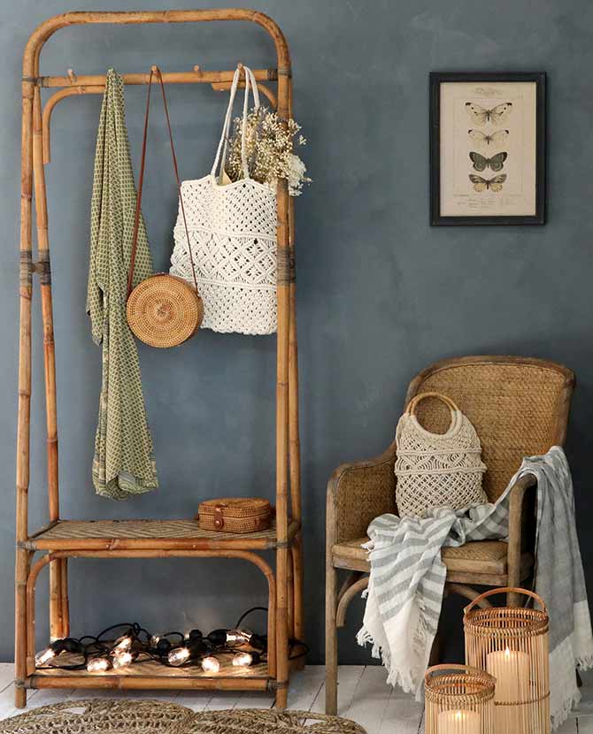 Vintage stílusú, autentikus, kör formájú, növényi rattanból és bőrből készült kézműves női táska bambusz fogason kék színű fal előtt