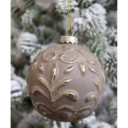 Vintage stílusú, aranyszínű növényi dombormintával díszített, gömb formájú, mokkaszínű üveg karácsonyfadísz, havas fenyőfán.