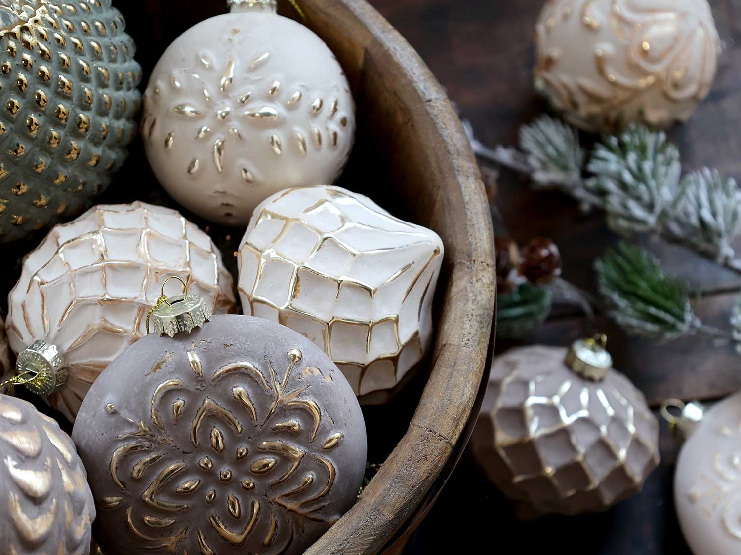 Aranyszínű dombormintával díszített, vintage karácsonyfadíszek fa tálban.