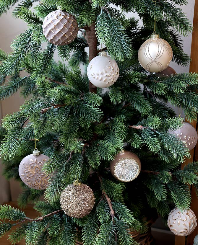 Aranyszínű dombormintával díszített, vintage karácsonyfadíszek zöld fenyőfán.