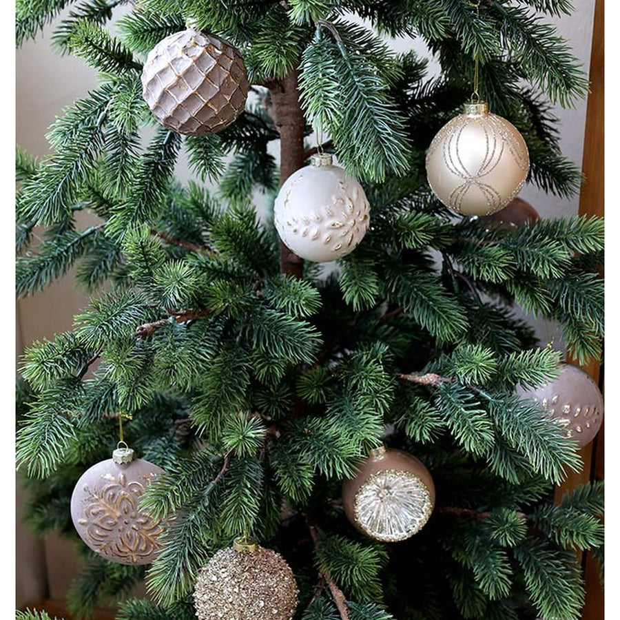 Aranyszínű dombormintával díszített, vintage karácsonyfadíszek zöld fenyőfán.