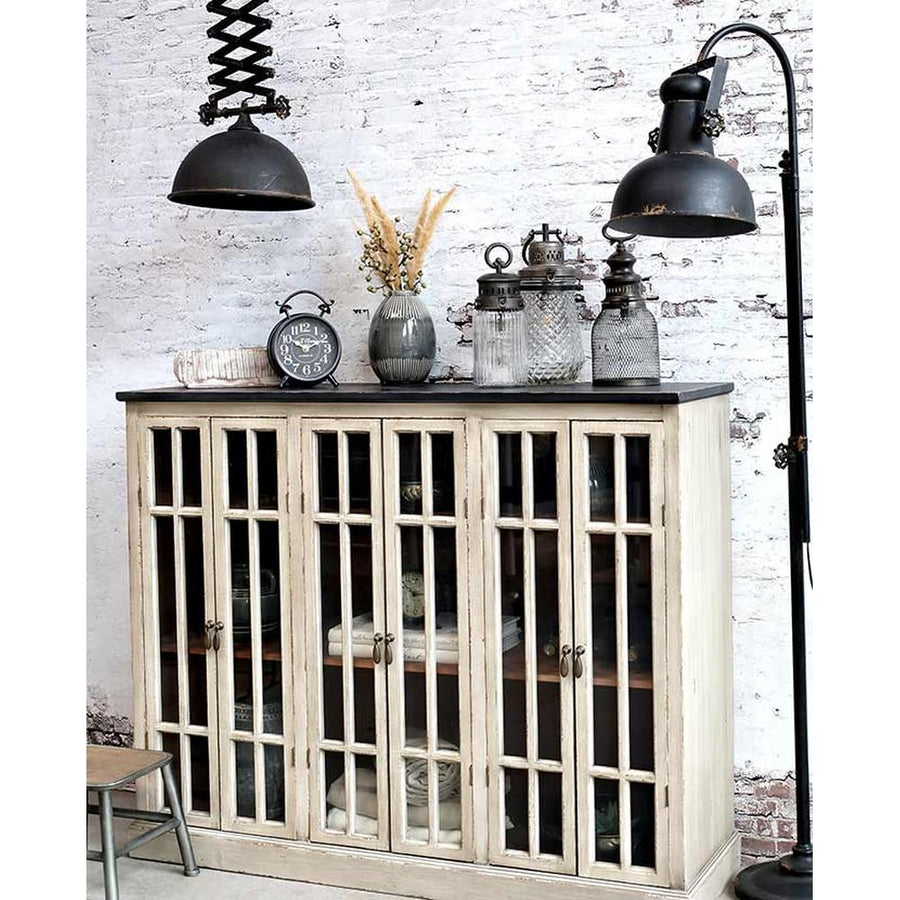 Vintage stílusú, fenyőfából készült, 123 cm hosszú, osztott üvegű, 6 ajtós antikolt vitrines tálaló fehér téglás fal előtt loft fém lámpákkal